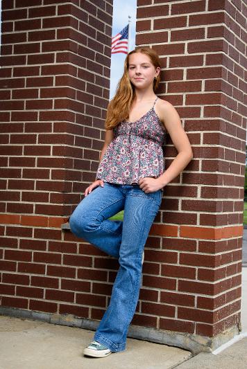high school gril leaning against a brick wall